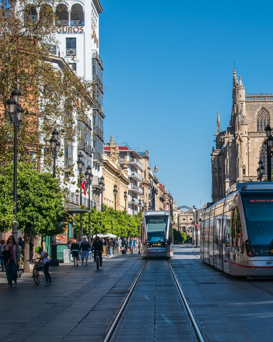 Avenida residencial moderna de Sevilla con bloques altos, aceras anchas y coches aparcados en fila