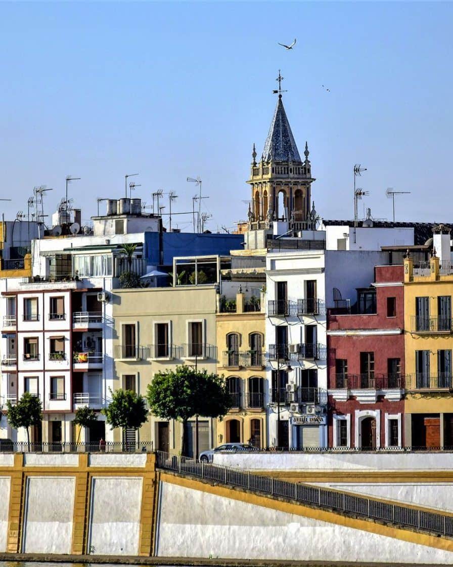 Terrasses au bord du fleuve dans la Calle Betis à Séville au coucher du soleil, avec le centre historique éclairé sur l'autre rive du Guadalquivir