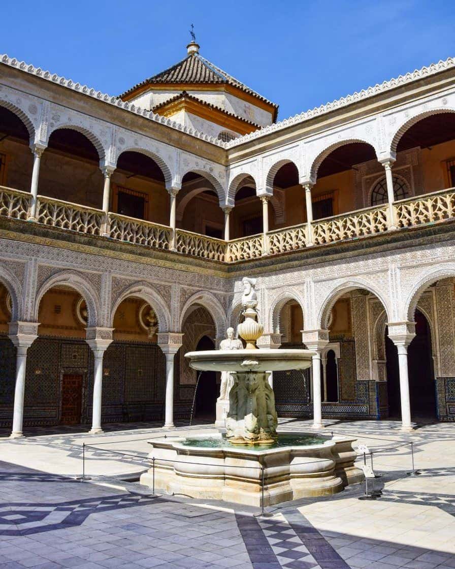Patio principal de la Casa de Pilatos à Séville, avec ses arcs mudéjars, ses azulejos et une fontaine centrale sous le soleil du matin