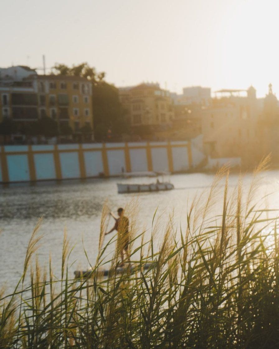 Rive du Guadalquivir à Séville au coucher du soleil, avec des promeneurs au bord du fleuve et le quartier de Triana sur l'autre rive