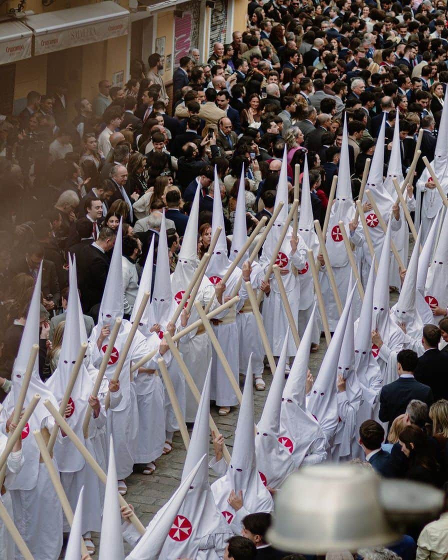 File de nazarenos portant des cierges dans une rue étroite de Séville pendant une procession de la Semaine sainte, de nuit
