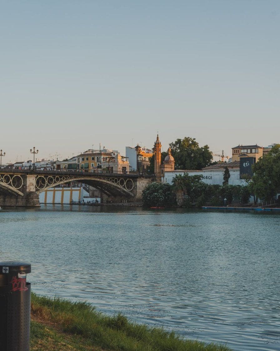 Triana bridge over the Guadalquivir in Seville at sunset, with an orange sky and no visible traffic